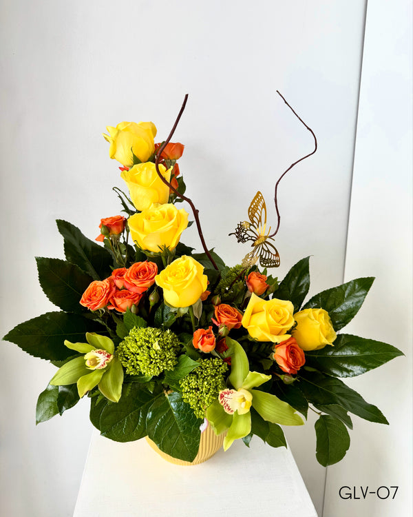 These stunning arrangement includes a mix of 6 roses, spray roses, and elegant cymbidium orchids, complemented by lush greenery. On ceramic vase and decorative detail. Perfect for adding a touch of natural beauty to any room.