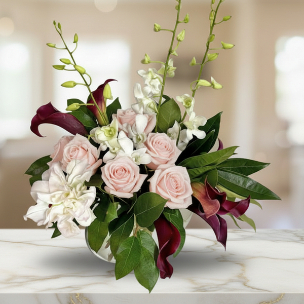 6 roses, 6 callas, lilies, and dendrobium orchids, with assorted greenery, on a glass vase.