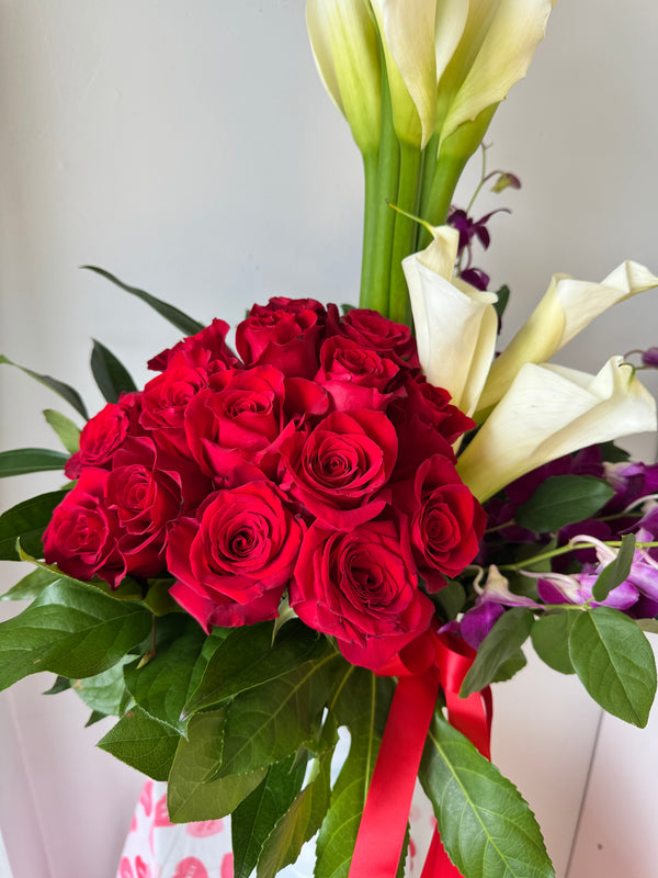 Featuring 18 roses, elegant calas, beautiful dendrobium orchids and mixed greenery, for a truly unique and vibrant display.