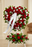 A heart shaped funeral standing wreath with red roses and white flowers, with a smaller elongated arrangement on the stand, by Gladys Flowers in Kendall, Miami.