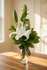 A small sympathy bouquet of white lilies and green foliage arranged in a clear glass vase by Gladys Flowers in Kendall, Miami.