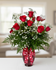Classic bouquet of 12 red roses in assorted colors with greenery in a glass vase